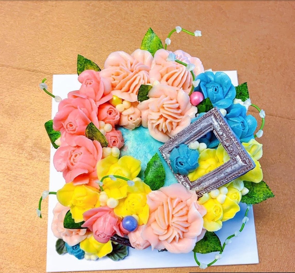 Sky blue cake with pink, blue and yellow flowers and a silver frame