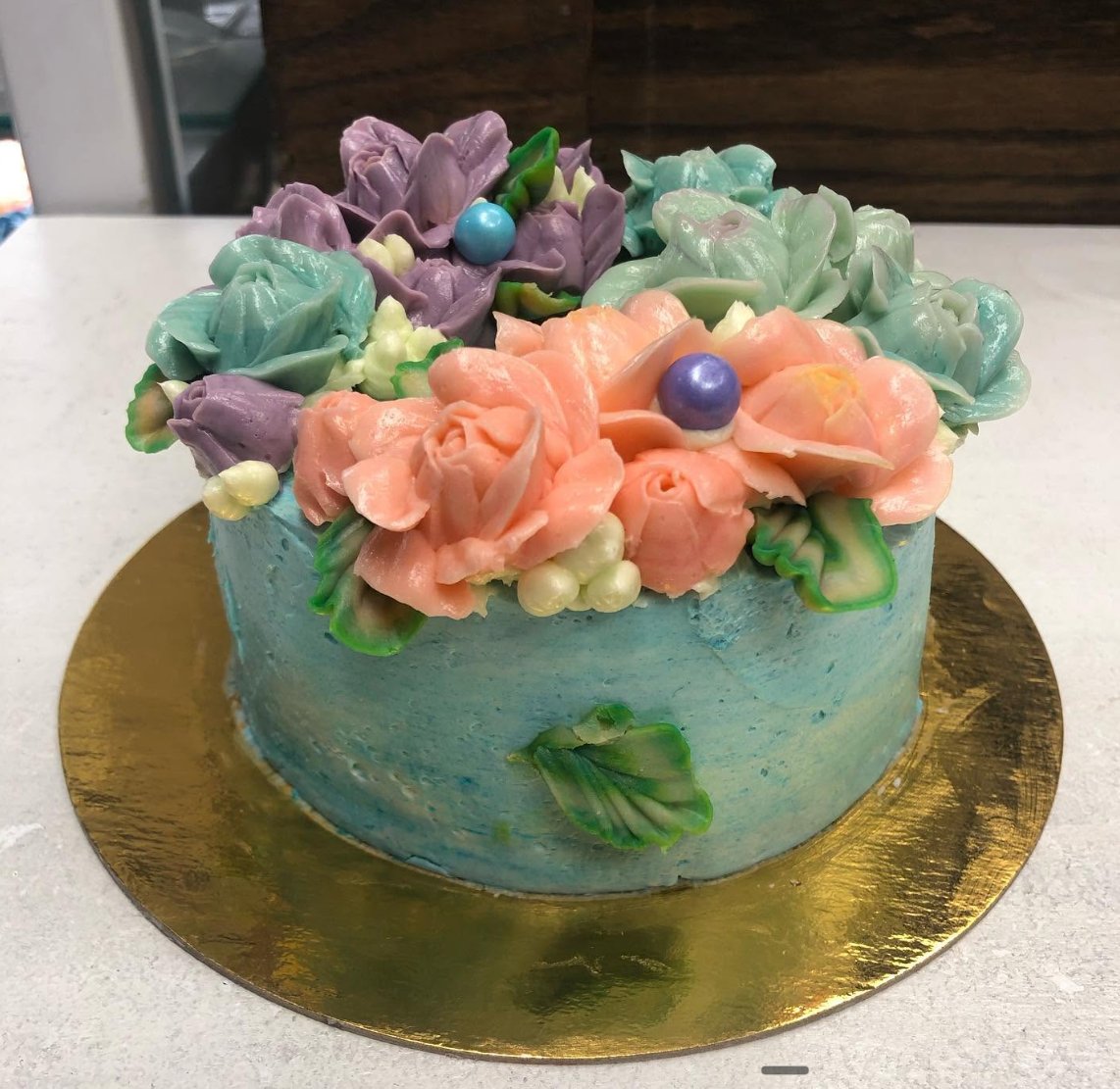 Light blue cake with peach and purple buttercream flowers