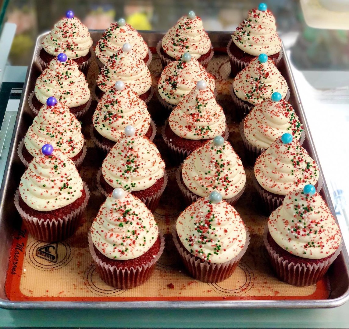 A tray of red velvet cupcakes with cream cheese icing and sprinkles