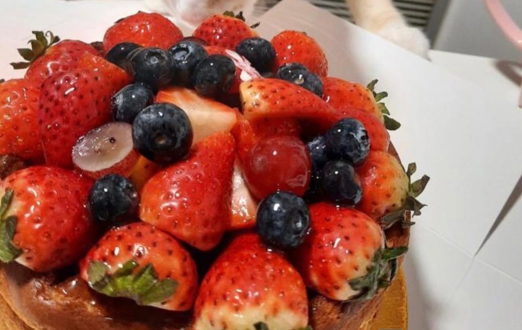 A fruit cake piled with glazed strawberries and blueberries