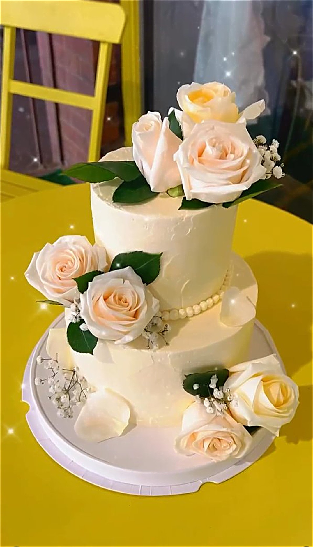 A two tier white wedding cake with fresh peach roses